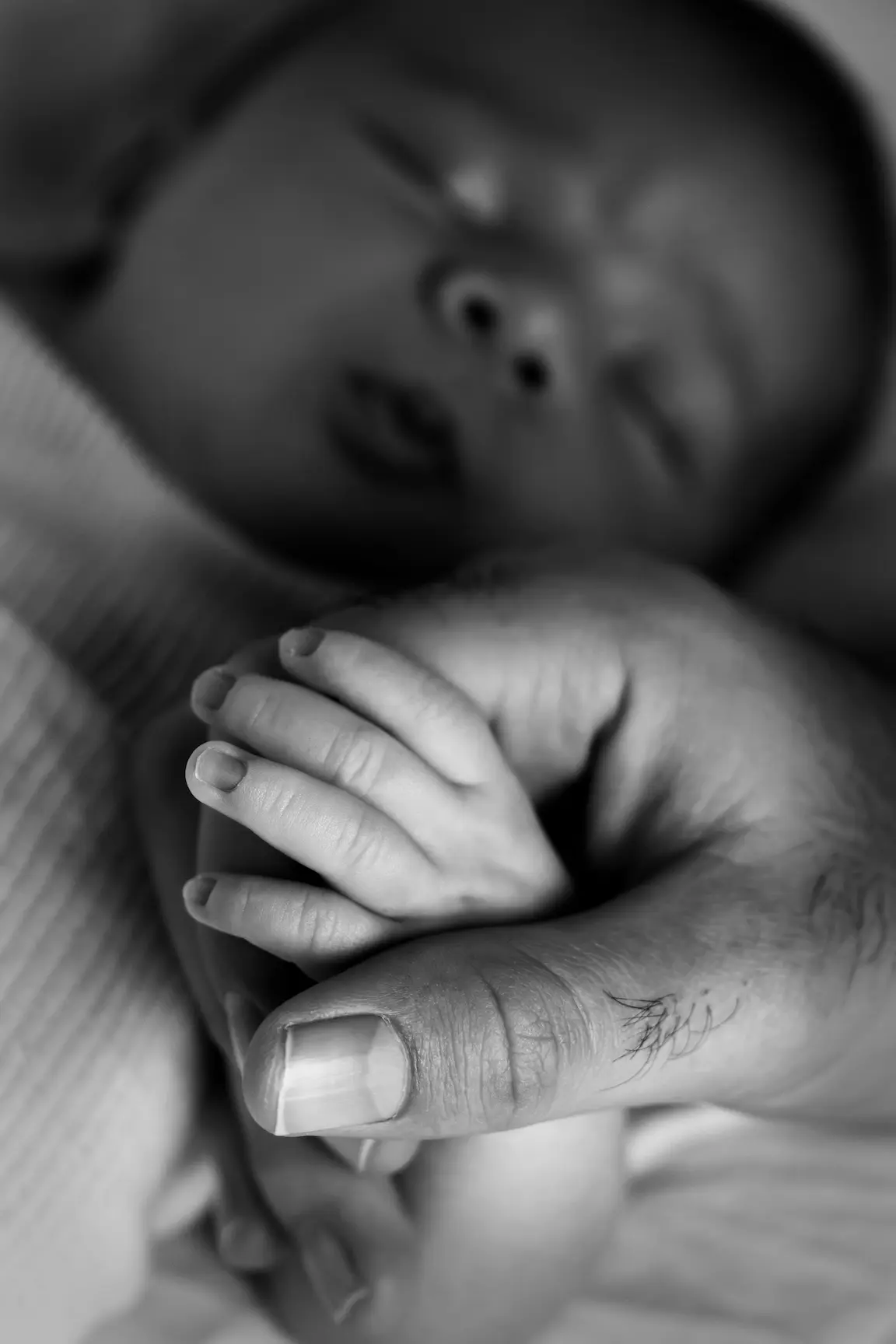 Main de nouveau-né tenant le doigt de son parent, connexion affective sécure et attachement